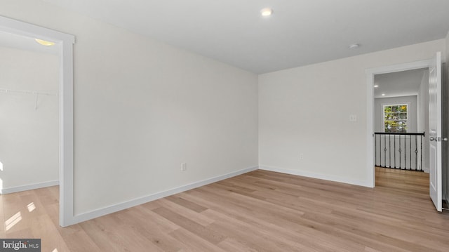 unfurnished bedroom with a walk in closet, a closet, and light wood-type flooring