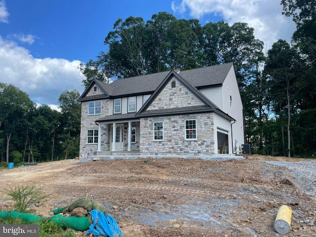 view of front of home featuring a porch, a garage, and central air condition unit