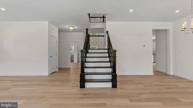 stairs featuring wood-type flooring and an inviting chandelier