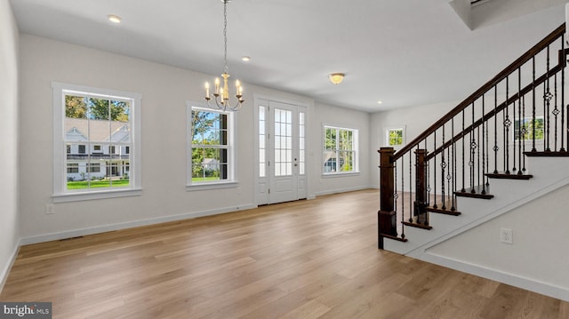 entrance foyer featuring light hardwood / wood-style floors, a healthy amount of sunlight, and an inviting chandelier