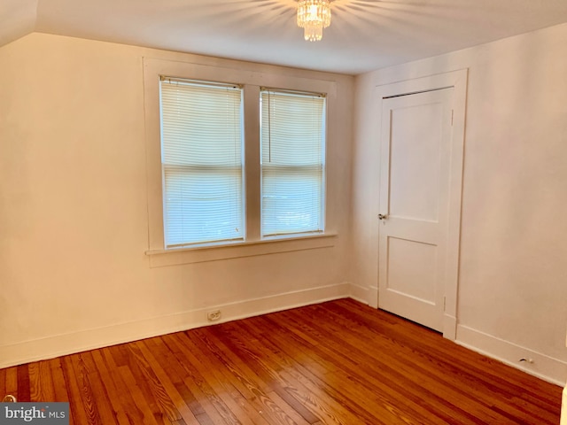 spare room with lofted ceiling, hardwood / wood-style floors, and a chandelier