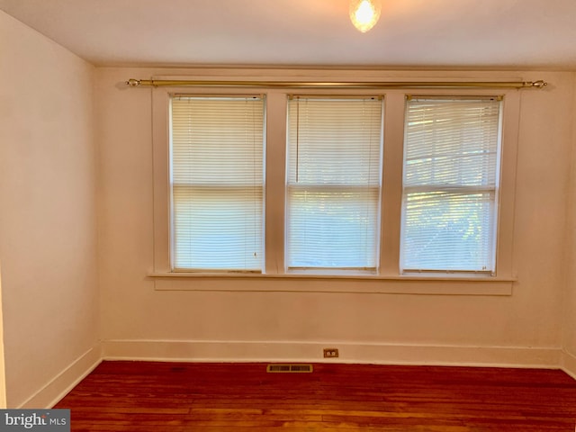 unfurnished room with a healthy amount of sunlight and dark wood-type flooring