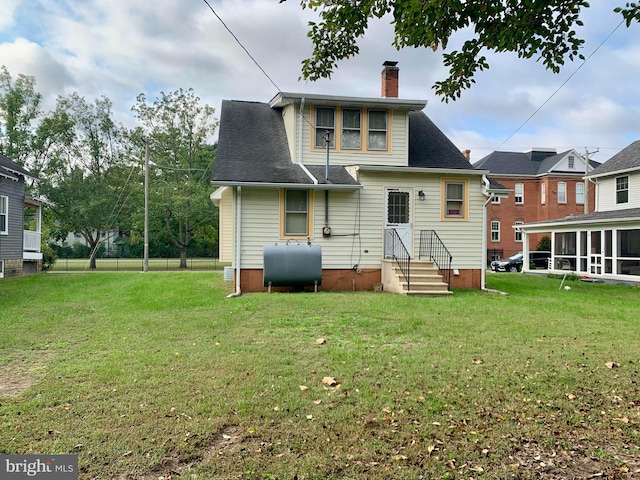 back of property featuring a sunroom and a lawn