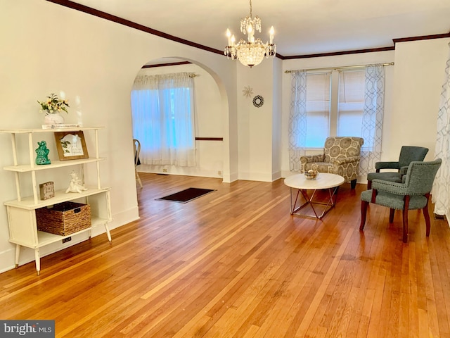 sitting room featuring wood-type flooring, ornamental molding, and a notable chandelier