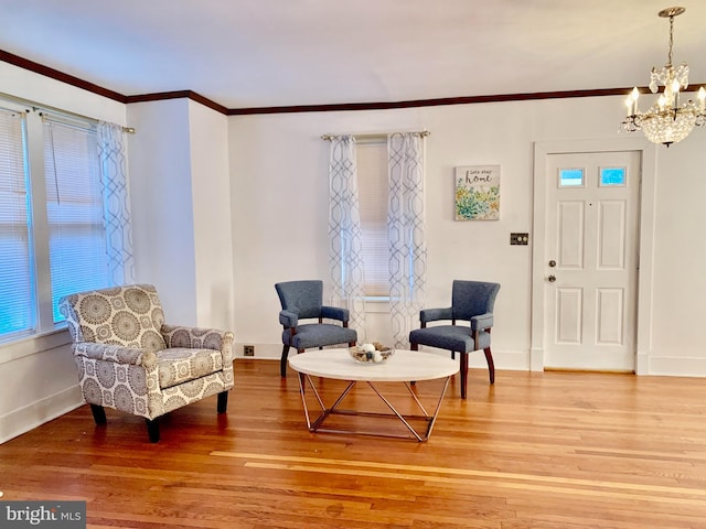 sitting room featuring crown molding, hardwood / wood-style floors, and an inviting chandelier