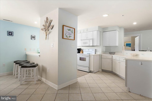 kitchen with white cabinets, light tile patterned floors, and white appliances