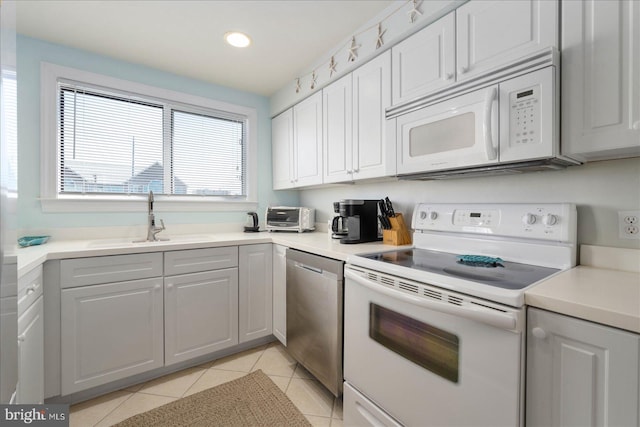 kitchen with gray cabinetry, white appliances, light tile patterned floors, and sink