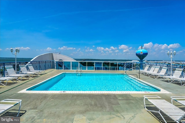 view of pool featuring a water view and a patio area