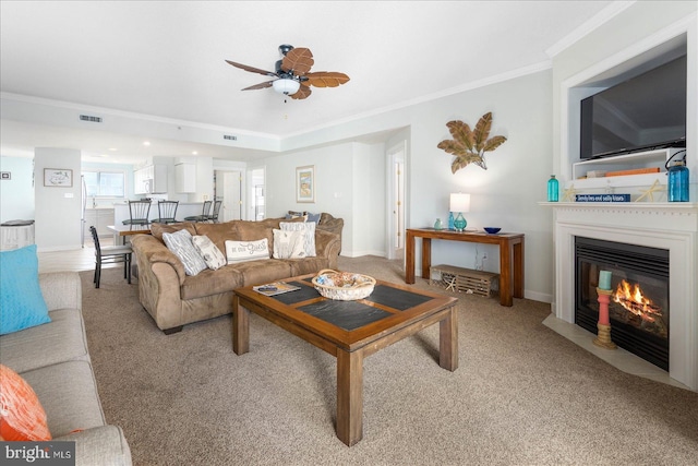 living room with ceiling fan, light colored carpet, and ornamental molding