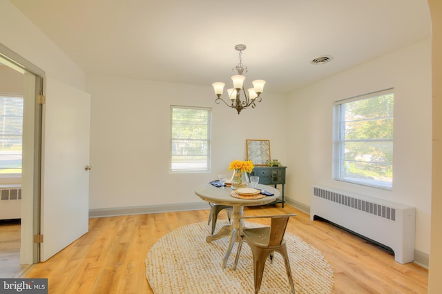 dining area with radiator, an inviting chandelier, and light wood-type flooring