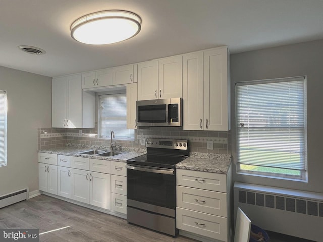 kitchen with radiator, stainless steel appliances, and white cabinets