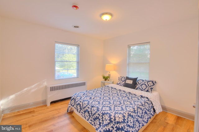 bedroom featuring radiator and hardwood / wood-style floors