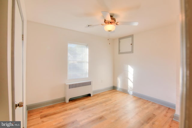 spare room with ceiling fan, light hardwood / wood-style floors, and radiator heating unit