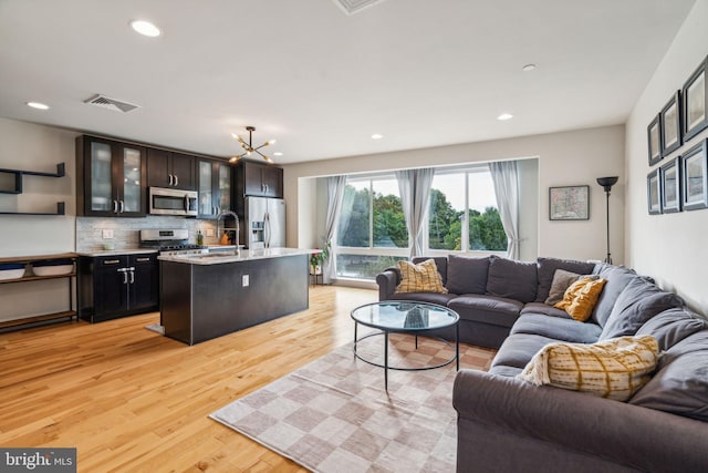 living room featuring light hardwood / wood-style floors, sink, and a chandelier