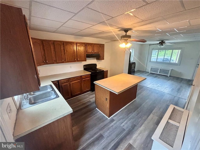 kitchen featuring electric range, dark wood-type flooring, sink, a kitchen island, and ceiling fan