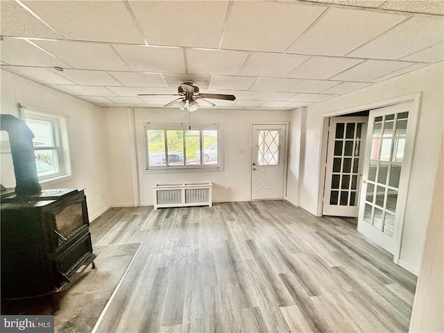 interior space with radiator, plenty of natural light, a wood stove, and a paneled ceiling