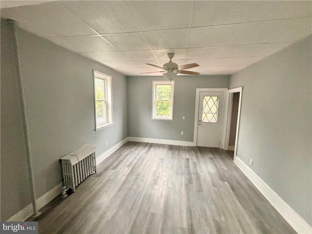 unfurnished living room featuring ceiling fan, hardwood / wood-style flooring, a paneled ceiling, and radiator heating unit