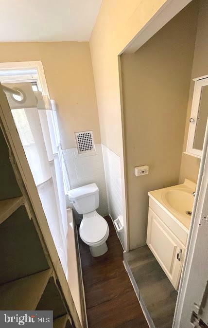 bathroom with tile walls, hardwood / wood-style floors, vanity, and toilet