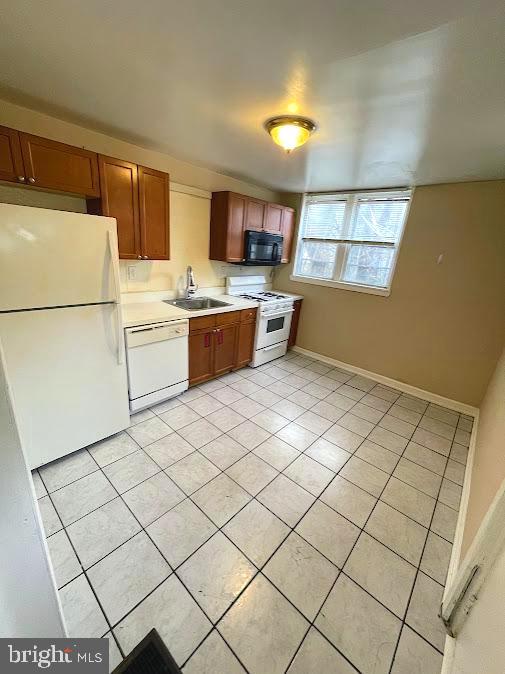 kitchen with white appliances, light tile patterned flooring, and sink