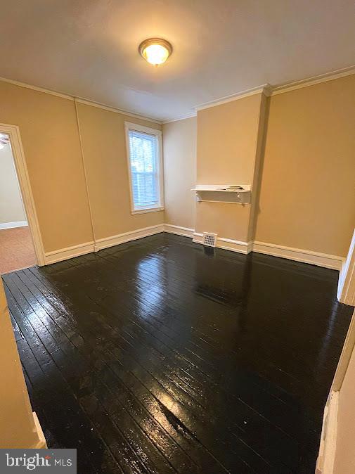 empty room featuring crown molding and hardwood / wood-style flooring