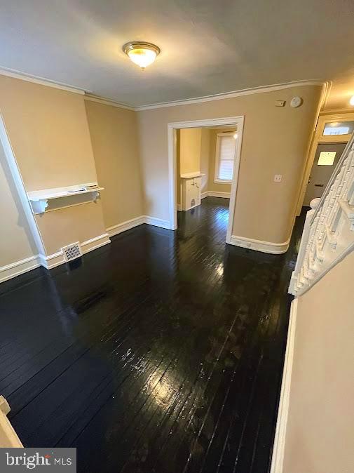 unfurnished room with crown molding and dark wood-type flooring