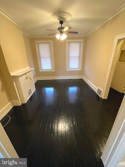 empty room featuring ceiling fan, dark hardwood / wood-style floors, and ornamental molding