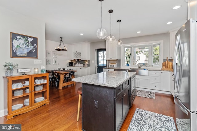 kitchen with white cabinetry, stainless steel refrigerator, sink, and a kitchen island