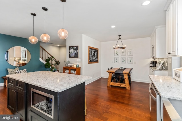 kitchen with a center island, white cabinetry, stainless steel appliances, pendant lighting, and dark hardwood / wood-style floors