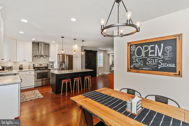 dining room with a notable chandelier, a barn door, and dark wood-type flooring