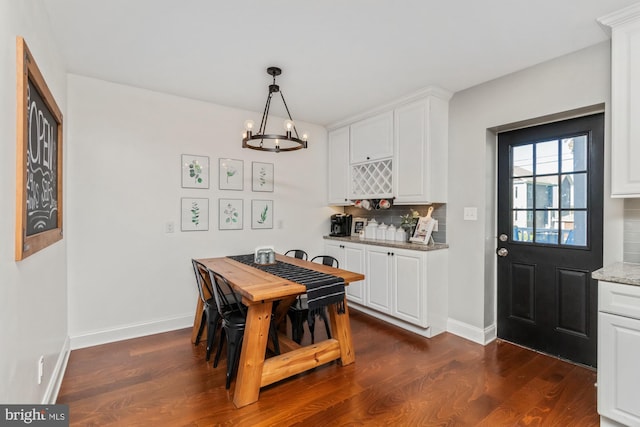 dining room with dark wood-type flooring and a notable chandelier