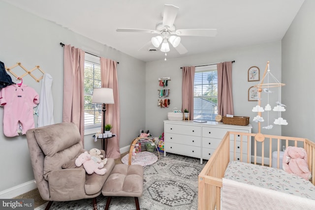 bedroom featuring multiple windows, a crib, and ceiling fan