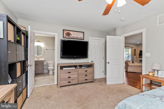 carpeted bedroom featuring ensuite bath and ceiling fan