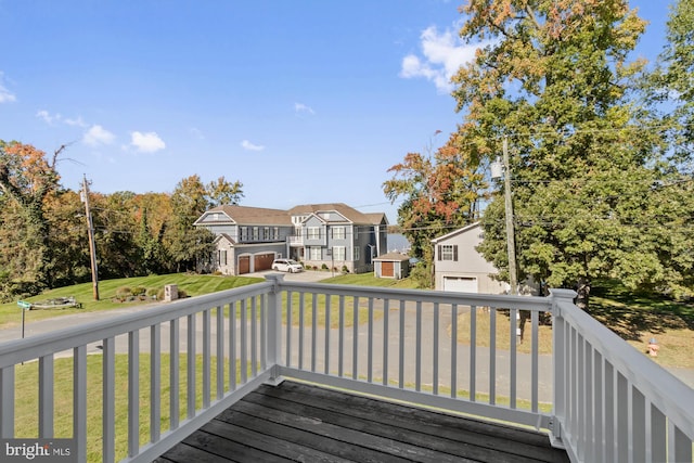 wooden terrace with a storage shed, a garage, and a lawn