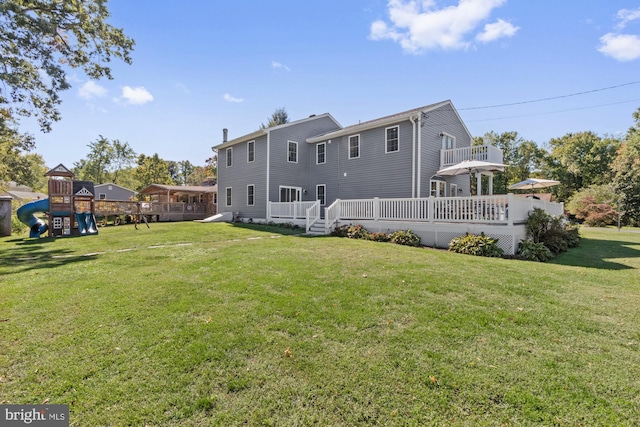 back of house featuring a wooden deck, a lawn, and a playground