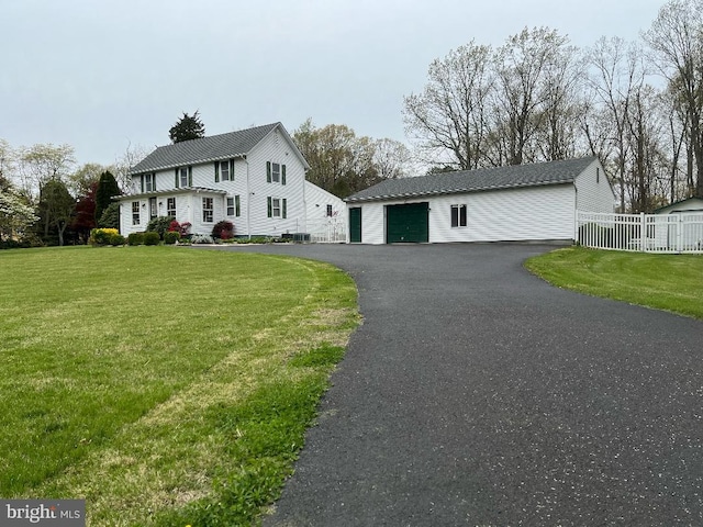 view of front of property with a garage, a front yard, and an outdoor structure