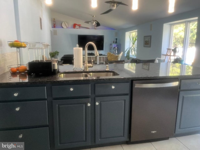 kitchen featuring lofted ceiling, light tile patterned floors, sink, stainless steel dishwasher, and dark stone countertops