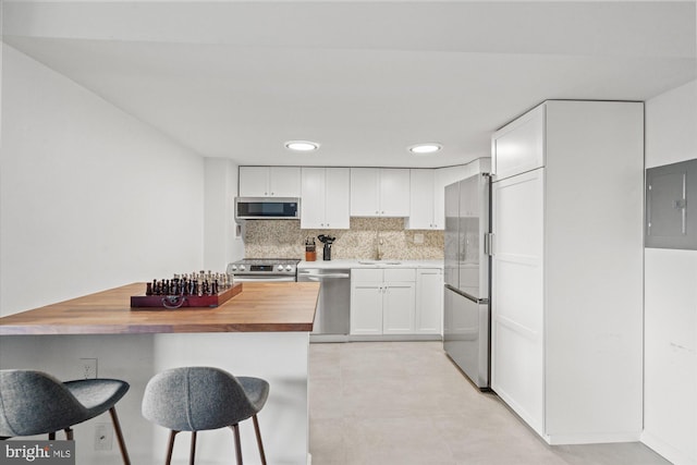 kitchen featuring appliances with stainless steel finishes, sink, wood counters, white cabinets, and electric panel