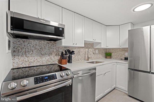 kitchen with stainless steel appliances, sink, white cabinets, light stone counters, and tasteful backsplash