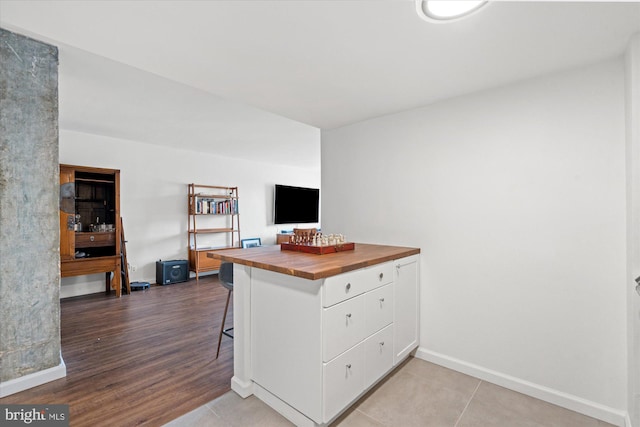 kitchen with light hardwood / wood-style flooring, white cabinetry, kitchen peninsula, and a breakfast bar