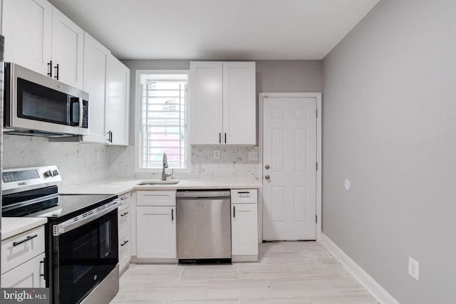 kitchen with white cabinets, stainless steel appliances, sink, and tasteful backsplash