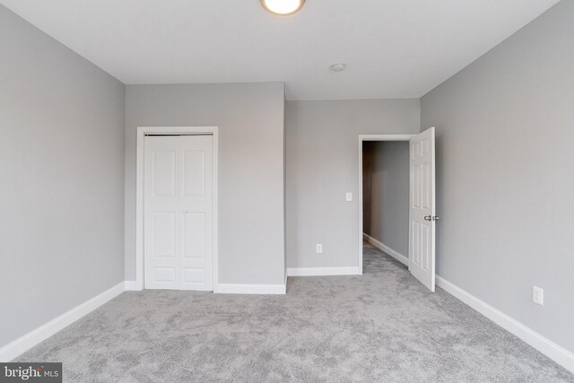 unfurnished bedroom featuring light colored carpet and a closet