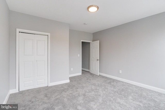 unfurnished bedroom with a closet and light colored carpet