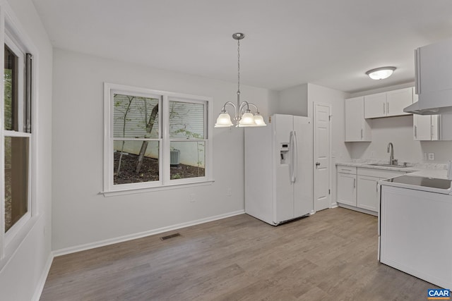 kitchen featuring hanging light fixtures, sink, light hardwood / wood-style flooring, white cabinetry, and white refrigerator with ice dispenser