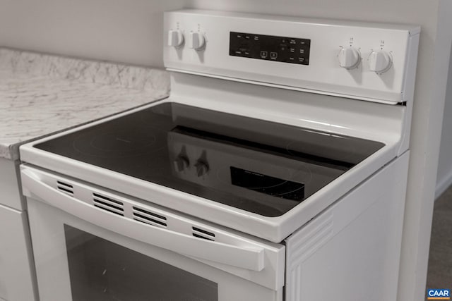 room details with white cabinetry and white range with electric stovetop