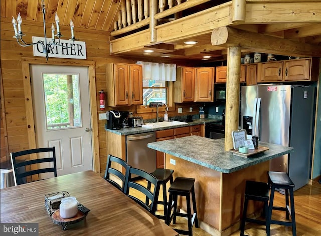 kitchen featuring sink, a kitchen island, light hardwood / wood-style flooring, stainless steel appliances, and wooden walls