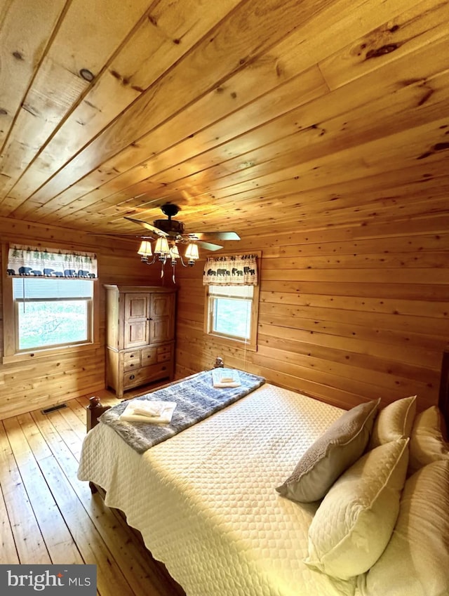 unfurnished bedroom featuring wood ceiling, wooden walls, ceiling fan, and hardwood / wood-style flooring