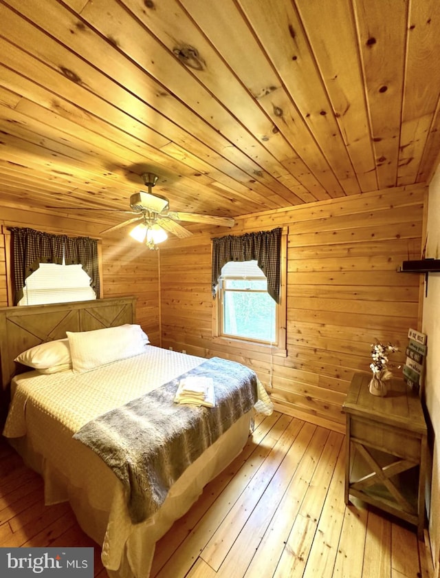 bedroom featuring ceiling fan, light wood-type flooring, wood ceiling, and wood walls