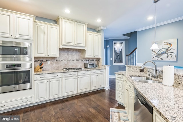 kitchen with appliances with stainless steel finishes, pendant lighting, crown molding, dark hardwood / wood-style floors, and sink