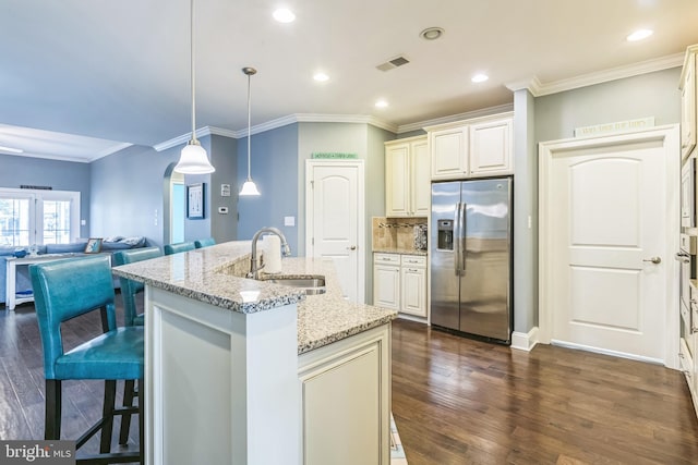 kitchen featuring light stone counters, dark hardwood / wood-style floors, sink, a center island with sink, and stainless steel fridge