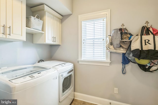 laundry room featuring washing machine and dryer, light tile patterned floors, and cabinets